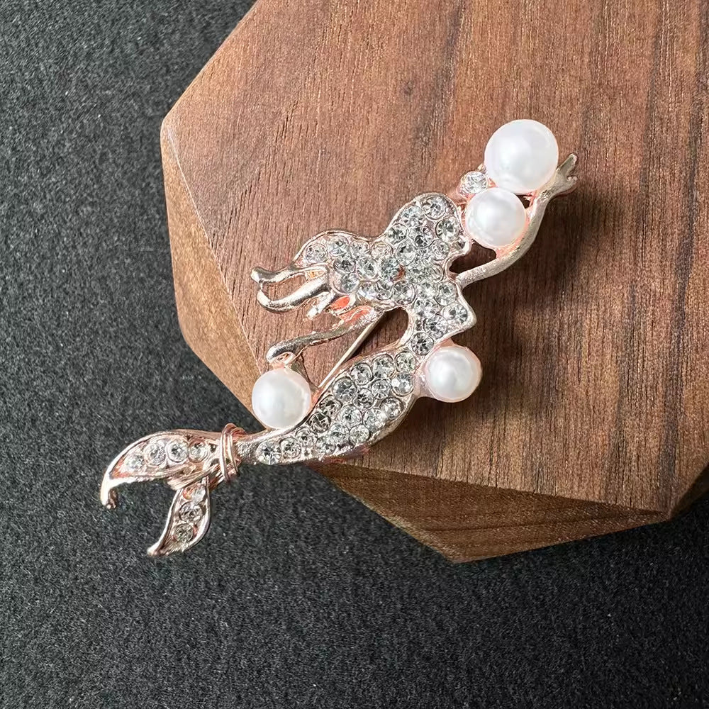 rosegold mermaid brooch against a dark background