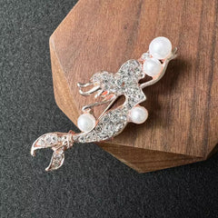rosegold mermaid brooch against a dark background